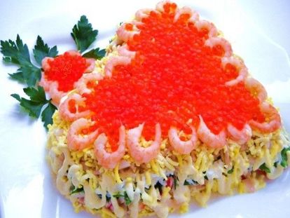 Салат с морепродуктами, выложенный в форме сердца и украшенный красной икрой и креветками, смотрится очень ярко и аппетитно.