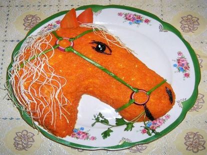 Еще одна лошадка, но уже огненная. Верхний слой выложен из вареной моркови. Уздечка из лука, глаза, нос и рот из маслин, грива из сыра &laquo;Косичка&raquo;.