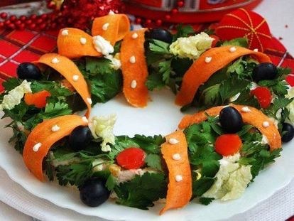 Салат в виде рождественского венка смотрится очень красиво. Венок украшен петрушкой, маслинами, лентой из моркови.