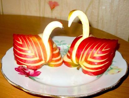 Из яблок многим нравится вырезать лебедей. Их пара, символизирующая вечную любовь, станет отличным украшением любого стола.