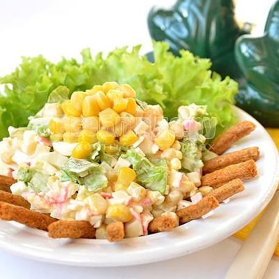 Салат с сухариками, крабовыми палочками, кукурузой, яйцами и листьями салата